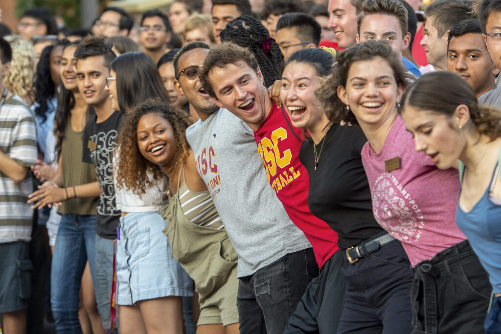 USC students link arms and smile at a Welcome Experience pep rally