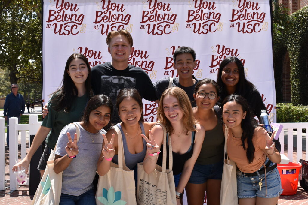 Image of USC students in front of a banner that has "You Belong at USC" repeated